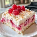 A slice of Raspberry Zinger Poke Cake topped with whipped cream and shredded coconut on a white plate