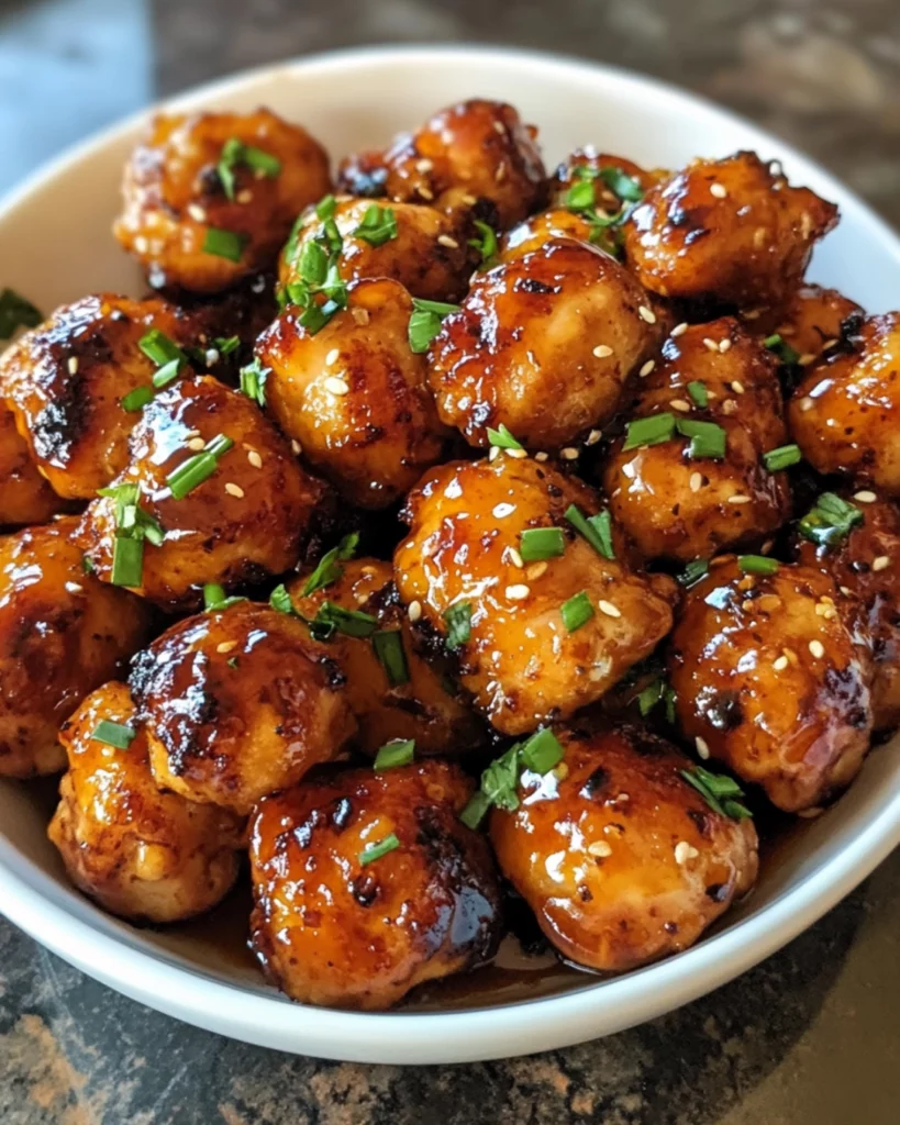 Crispy, golden-brown chicken bites coated in a sticky, smoky honey garlic glaze, garnished with sesame seeds and fresh parsley.