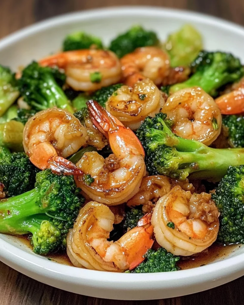 A plate of stir-fried shrimp and broccoli with a savory garlic-ginger sauce, served over steamed rice.