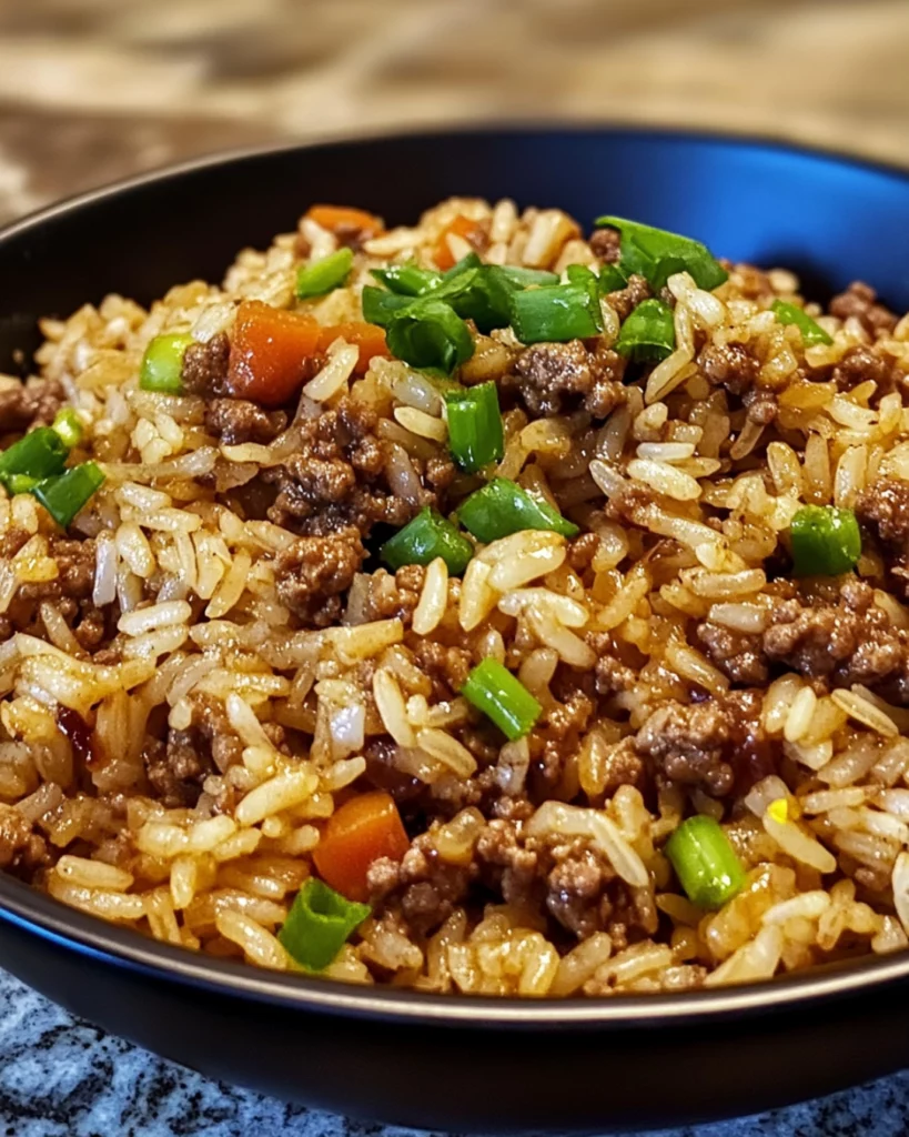 A plate of homemade Dirty Rice with Ground Beef, garnished with fresh green onions and parsley for a flavorful Southern-style meal.