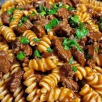 One-pan honey BBQ beef pasta with melted cheddar cheese in a skillet