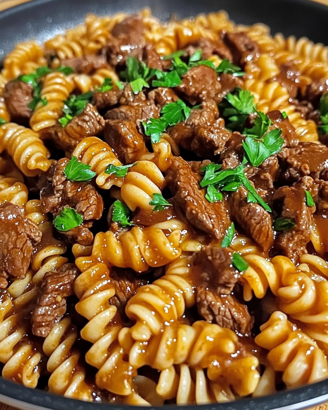 One-pan honey BBQ beef pasta with melted cheddar cheese in a skillet