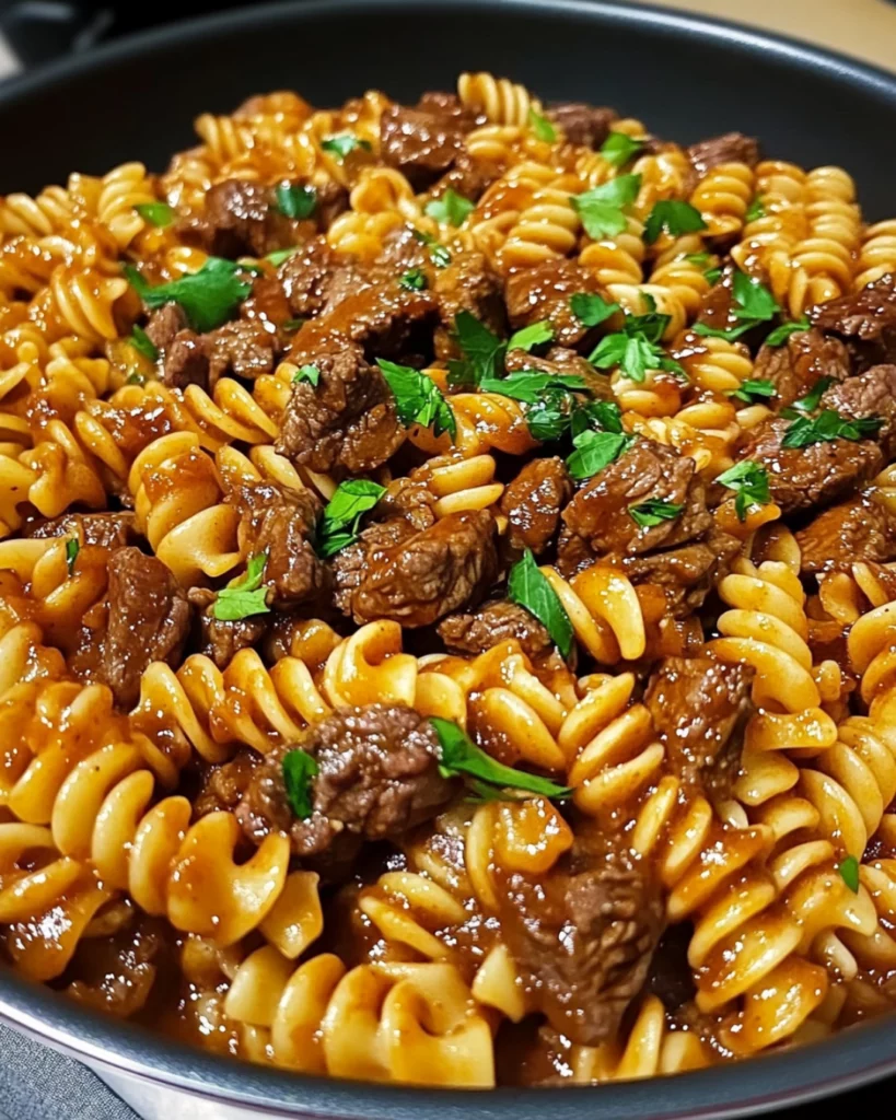 One-pan honey BBQ beef pasta with melted cheddar cheese in a skillet