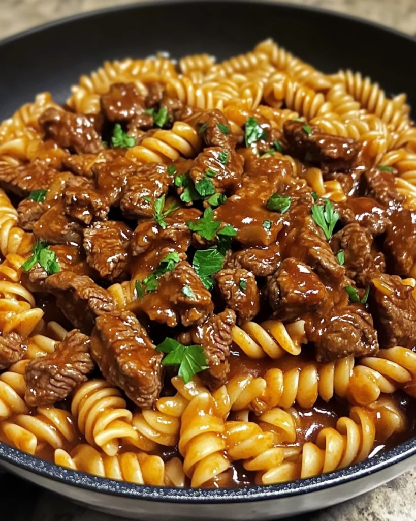 One-pan honey BBQ beef pasta with melted cheddar cheese in a skillet