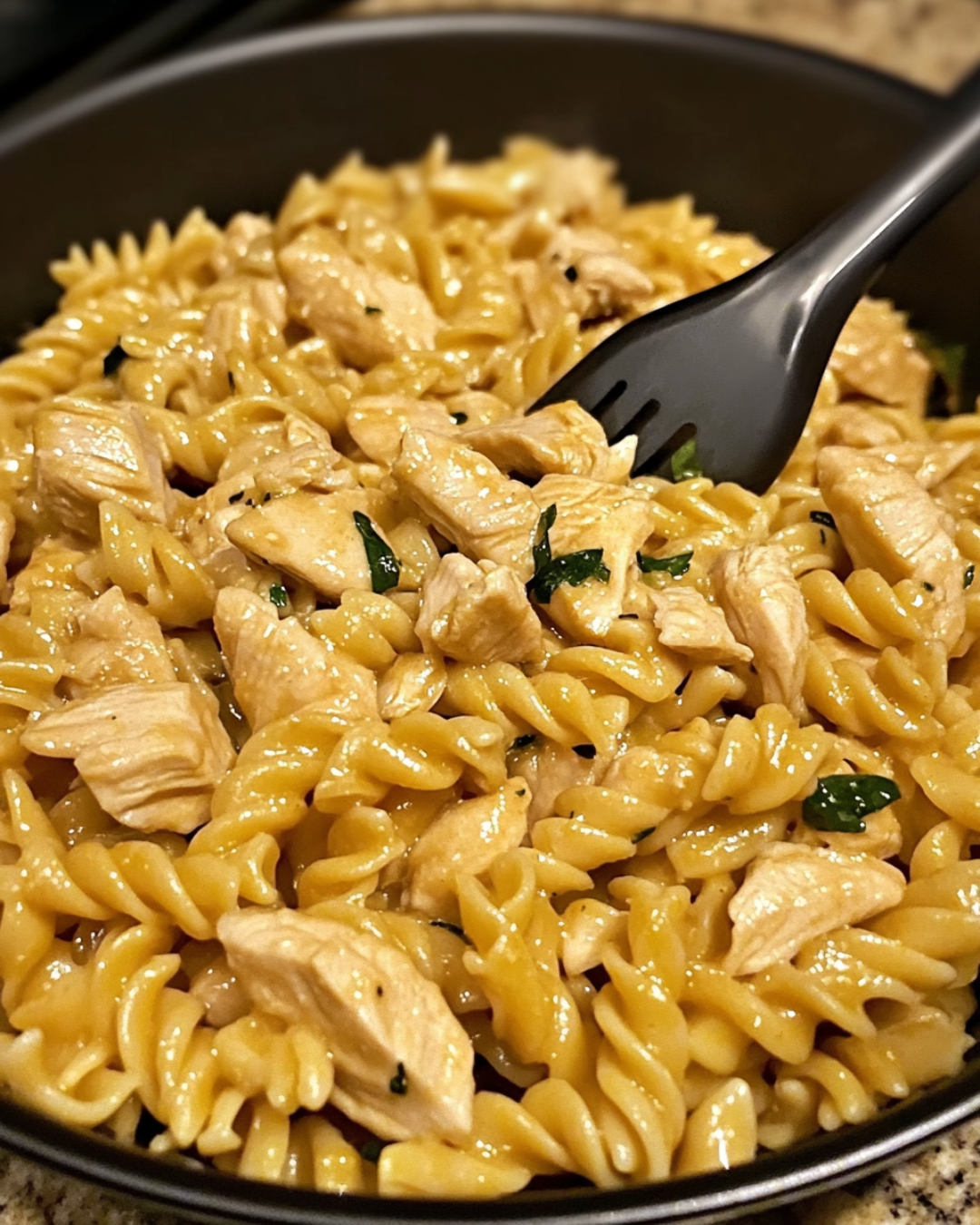 A bowl of creamy Hidden Valley Ranch Chicken Pasta with shredded cheese and parsley garnish, served on a rustic wooden table.
