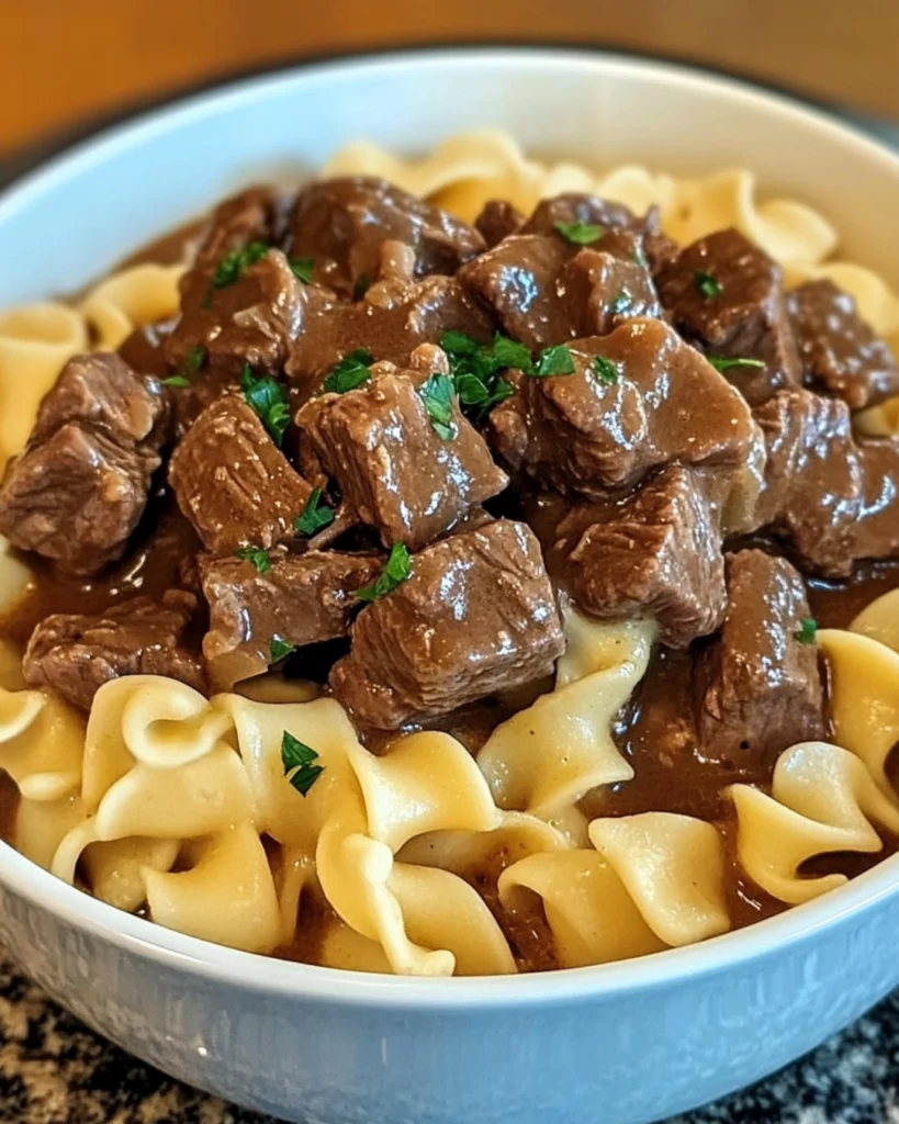Crockpot Beef Tips and Noodles served in a white bowl with parsley