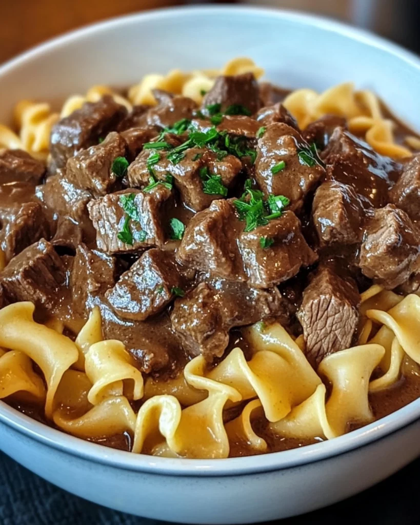 Crockpot Beef Tips and Noodles served in a white bowl with parsley