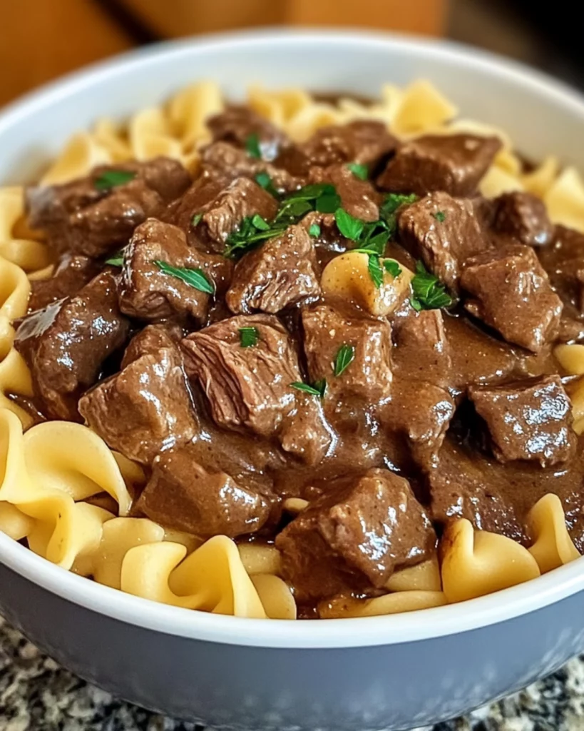 Crockpot Beef Tips and Noodles served in a white bowl with parsley